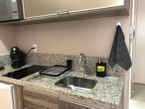 a kitchen counter with a sink and a stove at Flat 5 estrelas charmoso na Granja Viana in Cotia