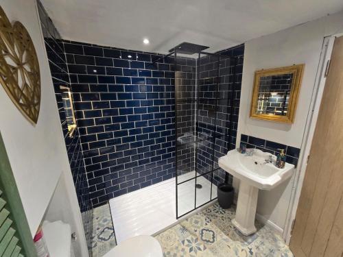 ein Badezimmer mit einem Waschbecken und einer Dusche mit blauen Fliesen in der Unterkunft Lakes Cottage Beckermet in Beckermet