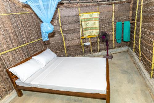 a small bed in a room with a fan at Barramundi in Puttalam