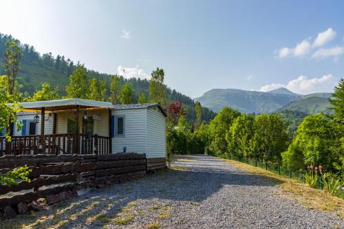 una pequeña casa blanca con una valla al lado de una carretera en Étoile du Cians Camping Beuil, en Beuil