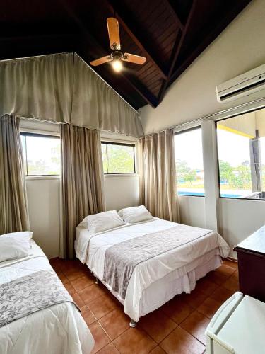 a bedroom with two beds and two windows at Pousada Villa Guimaraes in Chapada dos Guimarães
