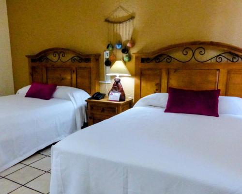 a bedroom with two beds and a phone on a table at Hotel Hacienda Bugambilias in La Paz
