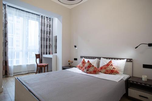 a bedroom with a bed with red and white pillows at Comfort City 3-Room Apartments in Almaty