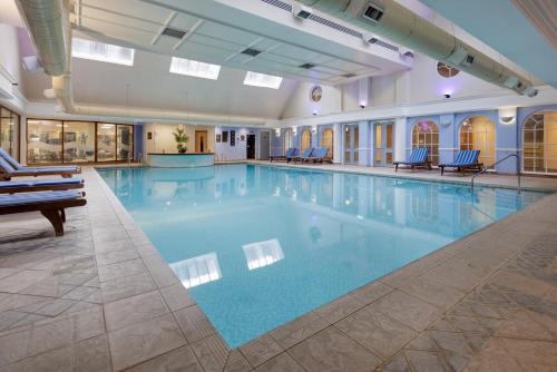 a large swimming pool with blue water in a building at DoubleTree by Hilton St. Anne's Manor in Bracknell