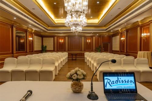 a conference room with white chairs and a laptop on a table at Radisson Hotel Jalandhar in Jalandhar