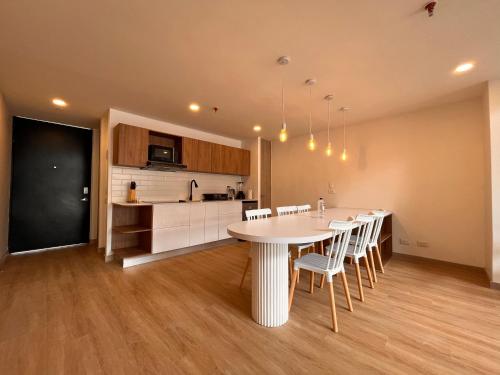 a kitchen and dining room with a white table and chairs at Enchanted Elegance in Laureles in Medellín