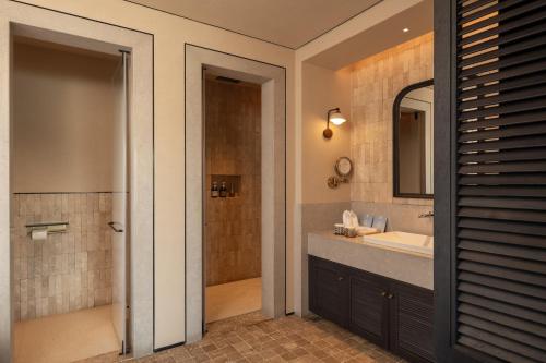 a bathroom with a sink and a shower and a mirror at 大理空山语 风眠艺术海景酒店 Dali Kongshanyu Art Seaview Hotel in Dali Airport