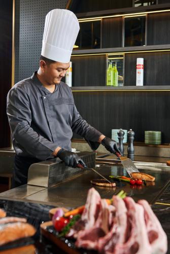 a man in a chefs hat preparing food in a kitchen at TRIMULIA Hotel in Sihanoukville