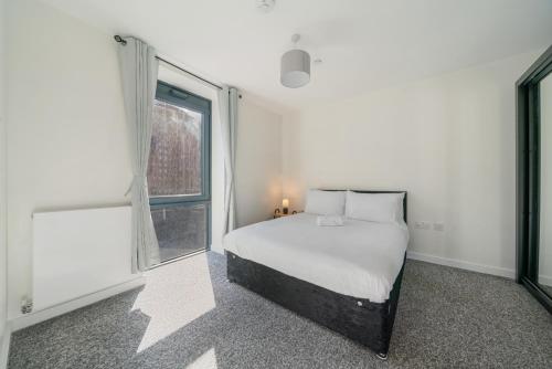 a white bedroom with a bed and a window at Wembley Stadium & OVO Apartment in London