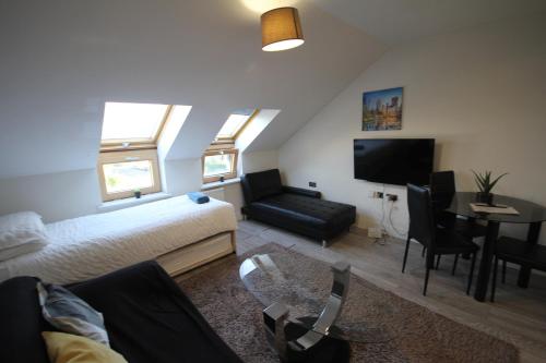a living room with a bed and a couch and a table at Holden Court Apartment 5 in West Drayton