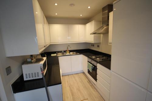a small kitchen with white cabinets and a sink at Holden Court Apartment 5 in West Drayton