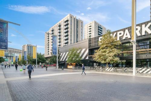 a city street with people walking in front of buildings at Wembley Stadium & OVO Apartment in London