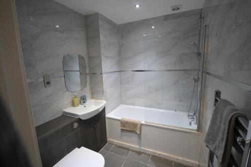 a bathroom with a tub and a sink and a toilet at Holden Court Apartment 5 in West Drayton