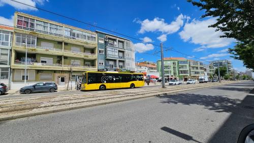 a yellow bus parked on the side of a city street at Almada Lisbon em frente dos transportes públicos in Almada
