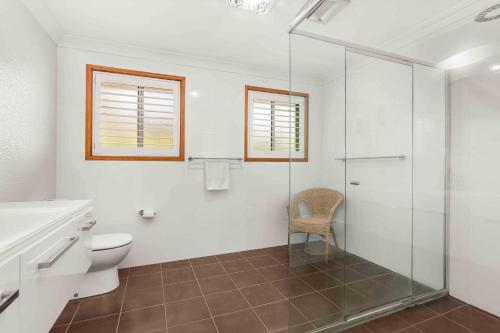 a bathroom with a toilet and a glass shower at Blenheim Hideaway by Experience Jervis Bay in Vincentia