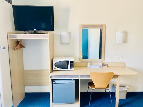 a room with a desk with a computer and a tv at Motel 6-Red Deer, AB in Red Deer