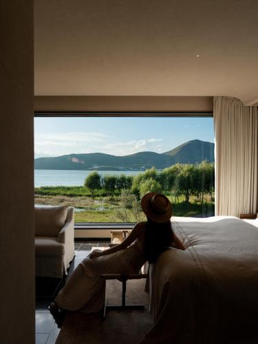 a woman sitting on a bed looking out a window at 大理空山语 风眠艺术海景酒店 Dali Kongshanyu Art Seaview Hotel in Dali Airport