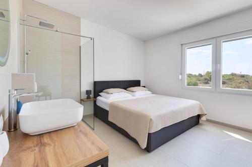 - une chambre blanche avec un lit et une baignoire dans l'établissement Villa Kotari in Zemunik Gornji - Haus für 10-12 Personen, à Simurina