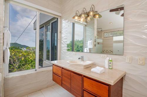 a bathroom with a sink and a large window at Villa Vista Bahia in Coco