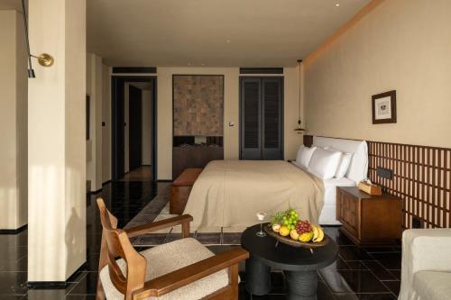 a hotel room with a bed and a table with a bowl of fruit at 大理空山语 风眠艺术海景酒店 Dali Kongshanyu Art Seaview Hotel in Dali Airport