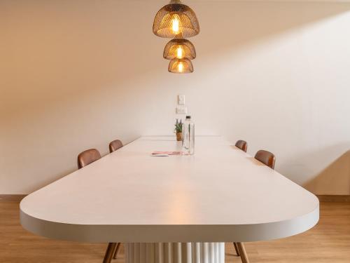 a white dining room table with chairs and a light fixture at Enchanted Elegance in Laureles in Medellín