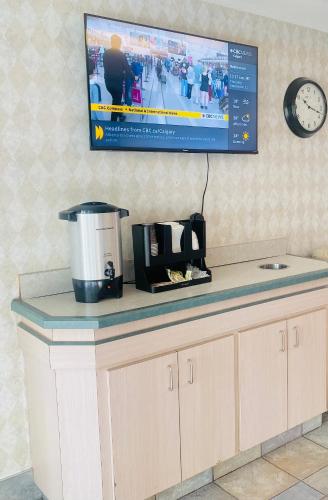 a counter with a coffee maker and a tv on the wall at Motel 6-Red Deer, AB in Red Deer