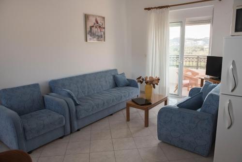 a living room with two blue couches and a table at Nephele Apartments in Faliraki