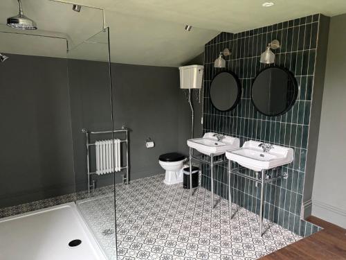 a bathroom with two sinks and a toilet and mirrors at The Old Posthouse in Scalby