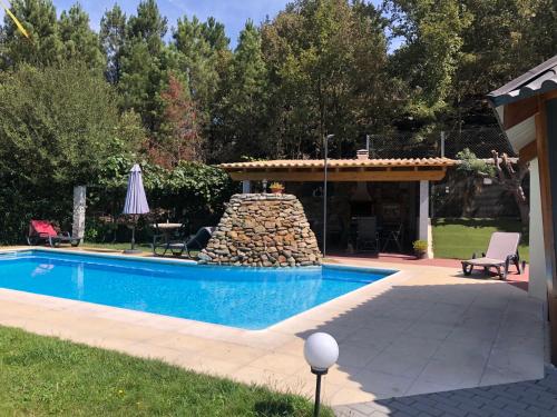 a swimming pool in a yard with a stone fountain at Quinta da Fervença, private river place to relax.. in Sernancelhe