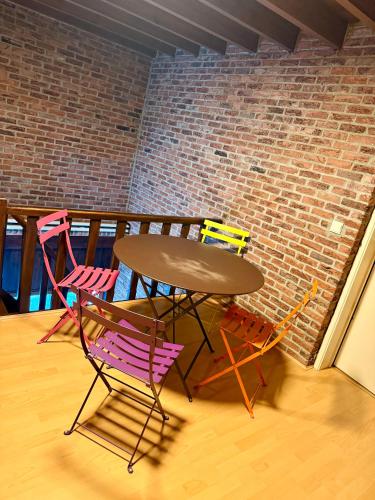 a table and four chairs sitting next to a brick wall at La Ferme des Roses in Tournai