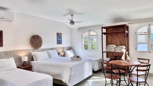 a bedroom with two beds and a table and chairs at Bella Buzios Apartamentos in Búzios