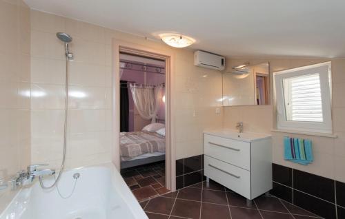ein Badezimmer mit Badewanne und Waschbecken und ein Bett in der Unterkunft Villa Davorka in Supetarska Draga - Haus für 8 Personen in Supetarska Draga