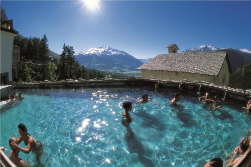 un groupe de personnes dans une piscine avec des montagnes dans l'établissement Baita Skianta, à Bormio