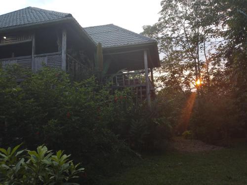 a house with a porch and a sunset in the background at Jungle Lodge Kibale in Kamwenge