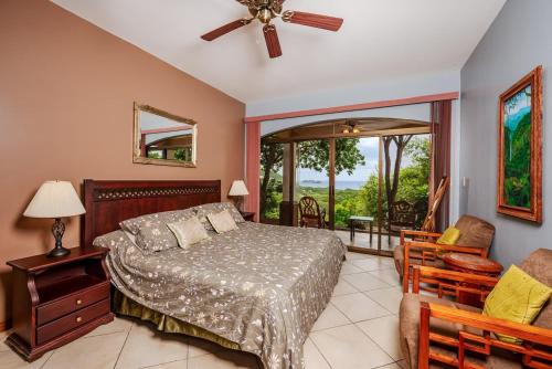 a bedroom with a bed and a chair and a window at Casa Lasky in Playa Hermosa