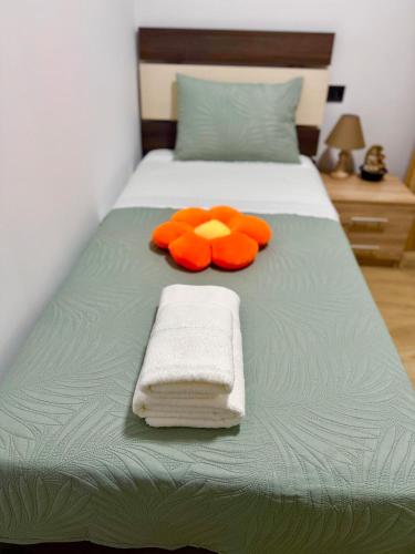 a bed with orange pillows and towels on it at VERORE aprtm in Chalkida