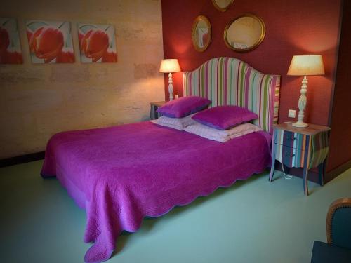 a bedroom with a purple bed with two purple pillows at Petit Garros in Fronsac