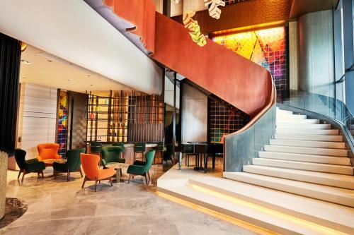 a staircase in a lobby with chairs and tables at TRIMULIA Hotel in Sihanoukville