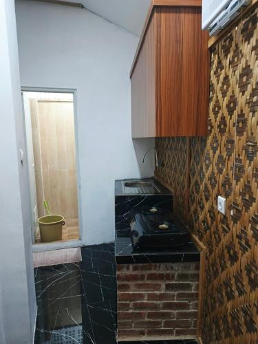 a kitchen with a stove and a brick wall at Jajapin Wangsaloka Syariah in Cijulang