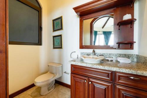a bathroom with a toilet and a sink and a mirror at Casa Texvol in Playa Hermosa
