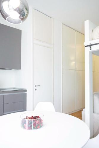 a white bedroom with a bowl of fruit on a bed at Tajani Room in Milan