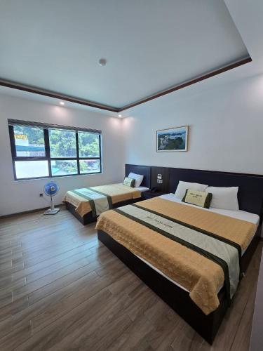 a bedroom with two beds and two windows at La Maison in Cat Ba