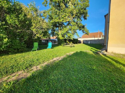 a yard with two green chairs and a table at Le Clos Mauron Numéro 13 in Gray-la-Ville