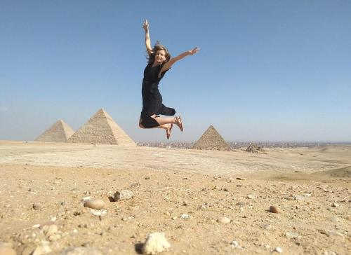 a woman jumping in the air in front of the pyramids at Pyramids golden rocks inn in Cairo