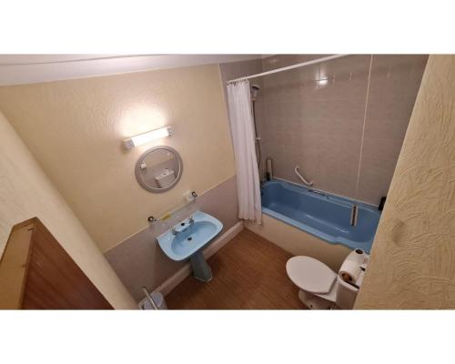 a bathroom with a blue tub and a toilet at Diamond Hotel in Torquay