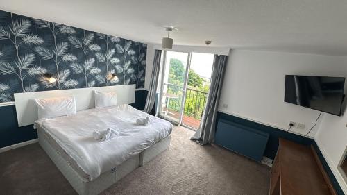 a bedroom with a bed with white sheets and a tv at Diamond Hotel in Torquay