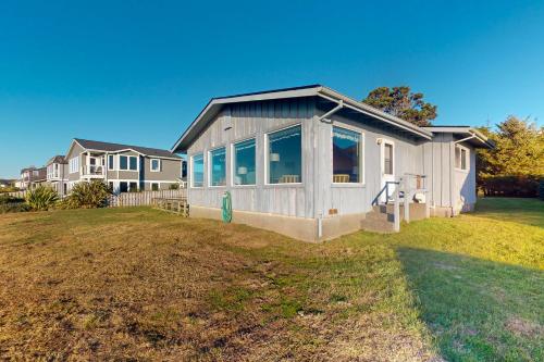 una piccola casa su un prato di fronte a una casa di Ocean Vista Cottage a Bandon