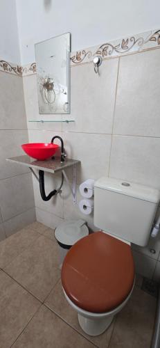 a bathroom with a toilet and a red sink at Pousada Mar Dos Anjos in Arraial do Cabo