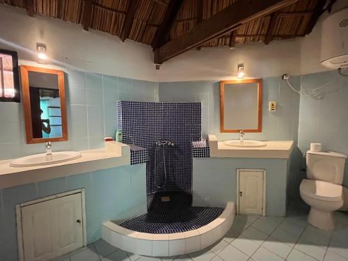a bathroom with two sinks and a shower and a toilet at The Grove 1-4 bedroom beachfront villa in Cap Skirring