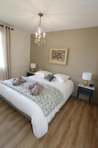 a bedroom with a large white bed and a chandelier at Villa Rosa in Roziers-dʼÉgletons